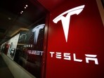 A sign bearing the Tesla company logo is displayed outside a Tesla store.