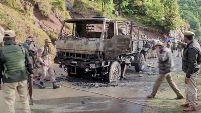 Armed security personnel walk at a site of an attack inspecting charred army vehicle in Poonch. (via Reuters.)