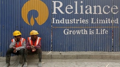 FILE PHOTO: Labourers rest in front of an advertisement of Reliance Industries Limited at a construction site in Mumbai. (REUTERS)