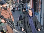 Afghanistan: A Taliban fighter stands guard as a woman walks past in Kabul, Afghanistan. Afghanistan: A Taliban fighter stands guard as a woman walks past in Kabul, Afghanistan.