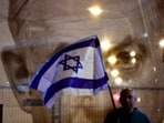 FILE PHOTO: A man holds an Israeli flag as he stands in front of a large picture of Israeli Prime Minister Benjamin Netanyahu.