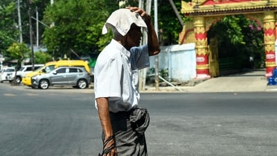 A man covers his head with a towel to shelter from the sun during a heatwave. (AFP)