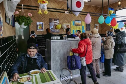 Fuminori Tsuchiko passes free food to people at his cafe. (REUTERS)
