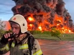 A firefighter speaks on the walkie talkie as smoke and flame rise from a burning fuel tank in Sevastopol, Crimea. 