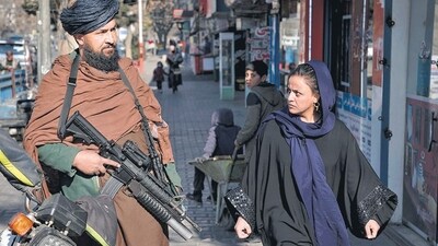 A Taliban fighter stands guard as a woman walks past in Kabul, Afghanistan. (AP) A Taliban fighter stands guard as a woman walks past in Kabul, Afghanistan. (AP)