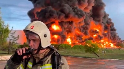 A firefighter speaks on the walkie talkie as smoke and flame rise from a burning fuel tank in Sevastopol, Crimea. (AP) A firefighter speaks on the walkie talkie as smoke and flame rise from a burning fuel tank in Sevastopol, Crimea. (AP)