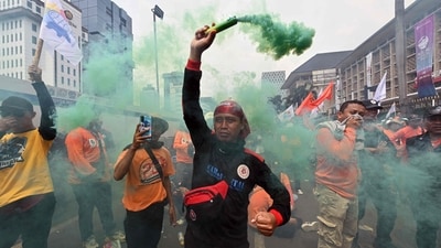 Demonstrators are seen popping coloured smoke as they take part in a Labour Day rally in Jakarta. (Adek Berry / AFP) Demonstrators are seen popping coloured smoke as they take part in a Labour Day rally in Jakarta. (Adek Berry / AFP)