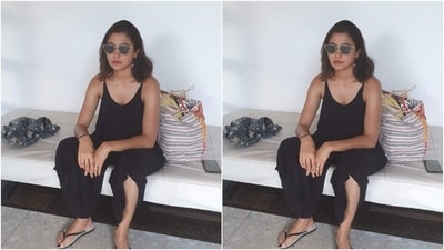 This picture shows Anushka dressed in a sleeveless black jumpsuit sitting with a sombre expression. She styled the outfit with sunglasses, earrings, rings, flip-flops, open tresses and a no-makeup look. (Instagram) This picture shows Anushka dressed in a sleeveless black jumpsuit sitting with a sombre expression. She styled the outfit with sunglasses, earrings, rings, flip-flops, open tresses and a no-makeup look. (Instagram)