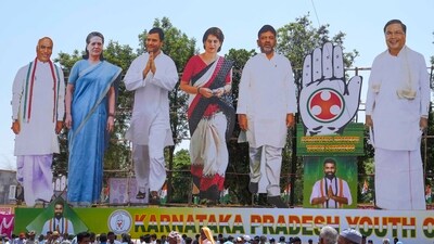 Congress supporters walk past giant cut-outs of senior party leaders in Karnataka’s Kolar. (PTI) Congress supporters walk past giant cut-outs of senior party leaders in Karnataka’s Kolar. (PTI)