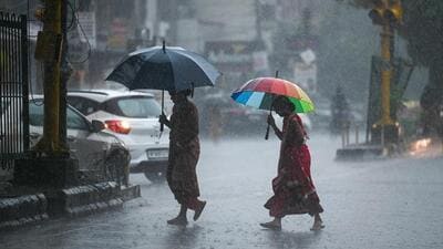 People cross a road during heavy rainfall in New Delhi on Monday. (Sanchit Khanna/HT PHOTO)