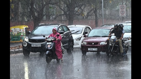 Commuters caught in the rain in Chandigarh on Monday. (Keshav Singh/HT)