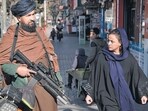 A Taliban fighter stands guard as a woman walks past in Kabul, Afghanistan. A Taliban fighter stands guard as a woman walks past in Kabul, Afghanistan.