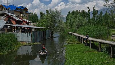 A man steers his boat in the interiors of Dal Lake on a sunny day in Srinagar on Friday. (AFP)