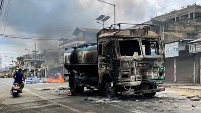 A scooterist rides past a damaged water tanker that was set afire during a protest by tribal groups in Churachandpur in Manipur. (REUTERS)