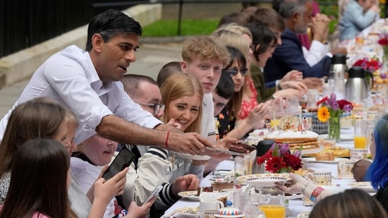 Britain's Prime Minister Rishi Sunak serves food to guests during a Coronation Big Lunch organised in Downing Street, in London, on Sunday.(AFP)