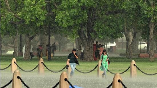 People caught in the rain at Kartavya Path in New Delhi on Sunday. (Hindustan Times)