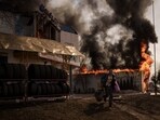 A man runs with items recovered from a burning shop following a Russian attack in Kharkiv, Ukraine, on March 25, 2022. The war between Russia and Ukraine began on February 24, 2022, and is still going on. In a report published by Reuters on April 12, the death toll of Russian and Ukrainian soldiers had reached 354,000 with thousands of civilian deaths.&nbsp;
