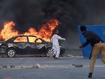 A policeman (R) throws a stone towards Pakistan Tehreek-e-Insaf (PTI) party activists and supporters of former Pakistan's Prime Minister Imran blocked a road in Karachi during a protest against his arrest. 