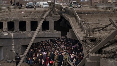 Ukrainians crowd under a destroyed bridge as they try to flee by crossing the Irpin River on the outskirts of Kyiv, Ukraine, on March 5, 2022. (Emilio Morenatti / AP)