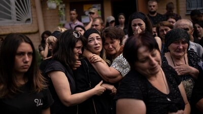 Anastasia Ohrimenko, 26, is comforted by relatives and friends as she cries next to a coffin with the body of her husband Yury Styglyuk, a Ukrainian serviceman who died in combat on Aug. 24 in Maryinka, Donetsk, during his funeral in Bucha, Ukraine, on August 31, 2022. (Emilio Morenatti / AP)