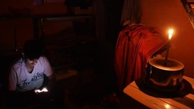 A person using a mobile phone in a candle-lit room during a power outage. (File) A person using a mobile phone in a candle-lit room during a power outage. (File)