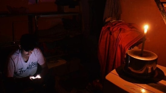 A person using a mobile phone in a candle-lit room during a power outage. (File)