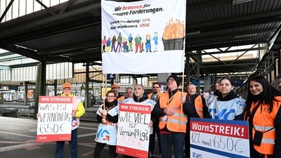 Railroad employees stand with banners on an empty platform at the main train station in Stuttgart, Germany, (AP)
