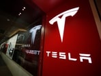 A sign bearing the Tesla company logo is displayed outside a Tesla store. A sign bearing the Tesla company logo is displayed outside a Tesla store.