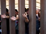 Migrants reach for water through the Mexico - U.S. border wall in San Luis Rio Colorado in Mexico, before the lifting of Title 42, as seen from San Luis, Arizona, U.S., May 11, 2023.