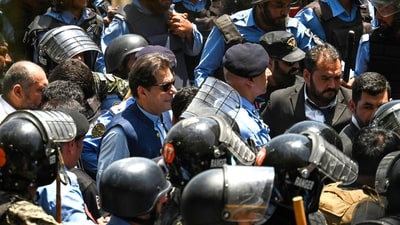 Policemen escort Pakistan's former Prime Minister Imran Khan (C) as he arrives at the high court in Islamabad on Friday. (AFP) Policemen escort Pakistan's former Prime Minister Imran Khan (C) as he arrives at the high court in Islamabad on Friday. (AFP)