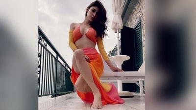 Mouni Roy's gorgeous outfit boasts a striking combination of orange and yellow hues. It comprises a bikini top, attached full sleeves, and a skirt with a daring thigh-high slit. (Instagram/@imouniroy) Mouni Roy's gorgeous outfit boasts a striking combination of orange and yellow hues. It comprises a bikini top, attached full sleeves, and a skirt with a daring thigh-high slit. (Instagram/@imouniroy)