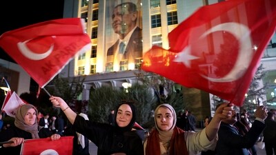 Supporters of Turkish president and the ruling Justice and Development (AK) Party wave flags as they wait for the results of Turkey's general elections at the AK Party headquarters in Ankara. (AFP)