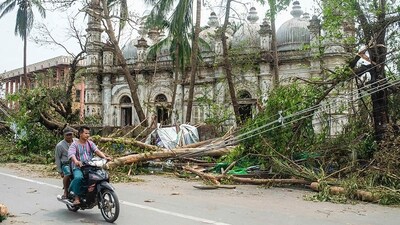Locals ride a motorbike on a road while fallen trees lie near a mosque after Cyclone Mocha made its landfall in Sittwe township, Rakhine State, Myanmar, on May 15. Communications were still mostly down and slowly being restored in Rakhine state's capital Sittwe, which is home to around 150,000 people, reported AFP. (AP ) Locals ride a motorbike on a road while fallen trees lie near a mosque after Cyclone Mocha made its landfall in Sittwe township, Rakhine State, Myanmar, on May 15. Communications were still mostly down and slowly being restored in Rakhine state's capital Sittwe, which is home to around 150,000 people, reported AFP. (AP )
