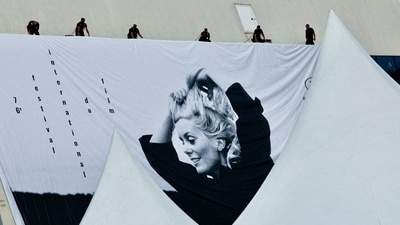 Workers set up a giant canvas of the official poster of the film ‘La Chamade,’ featuring actor Catherine Deneuve, on the facade of the festival palace ahead of the opening ceremony, The famous red carpet, traditionally 60 metres (yards) long, will be unrolled on Tuesday. In a nod to environmental concerns, its size has been cut in two to save some 1,400 kilos of carpet, reported AFP. (Eric Gaillard / Reuters) Workers set up a giant canvas of the official poster of the film ‘La Chamade,’ featuring actor Catherine Deneuve, on the facade of the festival palace ahead of the opening ceremony, The famous red carpet, traditionally 60 metres (yards) long, will be unrolled on Tuesday. In a nod to environmental concerns, its size has been cut in two to save some 1,400 kilos of carpet, reported AFP. (Eric Gaillard / Reuters)