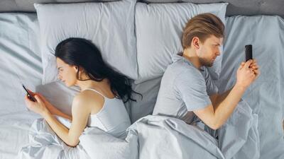 Alienated Millennial Young Couple in the Bed, Young People Turn Away From Each other Using Smartphones, Browsing Through Social Networks and Not Talking to Each Other. Top Down Shot. (Getty Images/iStockphoto) Alienated Millennial Young Couple in the Bed, Young People Turn Away From Each other Using Smartphones, Browsing Through Social Networks and Not Talking to Each Other. Top Down Shot. (Getty Images/iStockphoto)