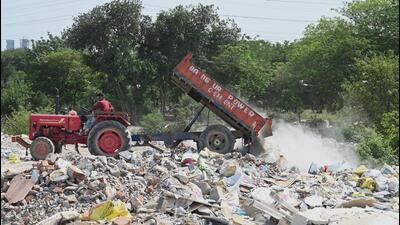 A tractor illegally dumps construction and demolition (C&D) waste on open land near an electricity substation in Sector-52 in Gurugram on May 6. (Parveen Kumar/HT Photo) A tractor illegally dumps construction and demolition (C&D) waste on open land near an electricity substation in Sector-52 in Gurugram on May 6. (Parveen Kumar/HT Photo)