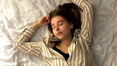 Sleeping on your back with a pillow under your knees: Sleeping on your back can also be a good option if you place a pillow under your knees, which helps ease the strain on your back and abdomen.&nbsp; (Unsplash)
