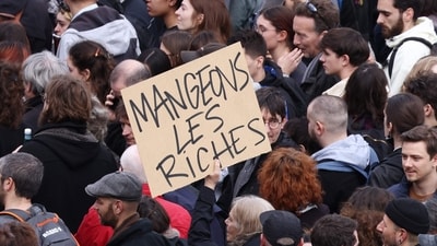 A protester holds a placard reads " Let's eat the rich" as they gahter in place de la Bastille square during a demonstration, in Paris (AFP) A protester holds a placard reads " Let's eat the rich" as they gahter in place de la Bastille square during a demonstration, in Paris (AFP)