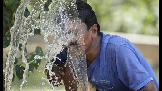 A person splashes water on his face from an irrigation pipe to beat the intense heat wave in Lucknow. (File Photo/AP)