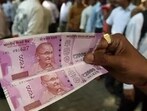 The image shows a person holding RS 2000 notes that the RBI asked banks to stop issuing. The image shows a person holding RS 2000 notes that the RBI asked banks to stop issuing.