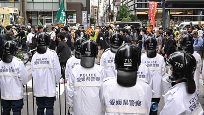 Police (foreground) monitor as a group of protesters (behind) march down a street to protest against the G7 Leaders' Summit on the first day of the gathering in the city of Hiroshima on May 19, 2023. (AFP)