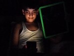 A boy entertaining himself with a smartphone amid a power outage in Mohali on Tuesday. (Ravi Kumar/HT)