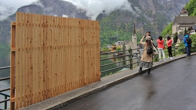 A provisional wooden fence is partially blocking the beautiful view, as visitors take selfies with the landscape, in the tourist community of Hallstatt (district of Gmunden), Austria, on May 15, 2023. The Austrian village of Hallstatt -- popular among selfie-seekers -- has installed wooden barriers to obstruct the view in an effort to curb overtourism and restore calm. (AFP) A provisional wooden fence is partially blocking the beautiful view, as visitors take selfies with the landscape, in the tourist community of Hallstatt (district of Gmunden), Austria, on May 15, 2023. The Austrian village of Hallstatt -- popular among selfie-seekers -- has installed wooden barriers to obstruct the view in an effort to curb overtourism and restore calm. (AFP)
