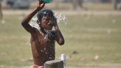 A slum kid cools off on a hot day at a public tap.