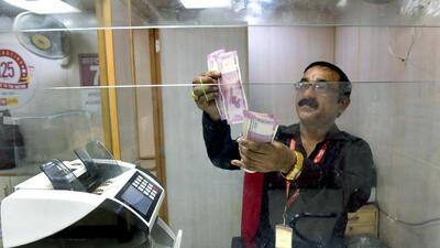 A banker checks the ₹2000 currency notes, in New Delhi on Saturday. (ANI) A banker checks the ₹2000 currency notes, in New Delhi on Saturday. (ANI)