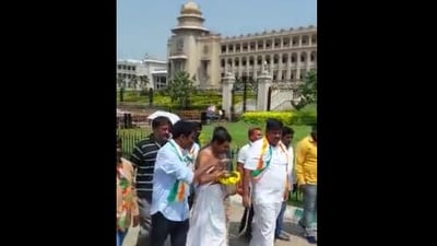 In a video, Congress workers are seen carrying a bucket all around the Karnataka Assembly filled with cow urine and were sprinkling it with leaves. (Twitter/ANI)