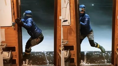 The image shows a person trying to close a door amid strong winds in Antarctica. (Instagram/@tomaszkurczaba) The image shows a person trying to close a door amid strong winds in Antarctica. (Instagram/@tomaszkurczaba)