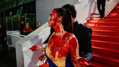 A protester, wearing a dress in the colours of the Ukrainian flag, was detained by security after she covered herself in fake blood on the stairs on the Festival Palace ahead of the screening of the film Acide during the 76th edition of the Cannes Film Festival (AFP) A protester, wearing a dress in the colours of the Ukrainian flag, was detained by security after she covered herself in fake blood on the stairs on the Festival Palace ahead of the screening of the film Acide during the 76th edition of the Cannes Film Festival (AFP)
