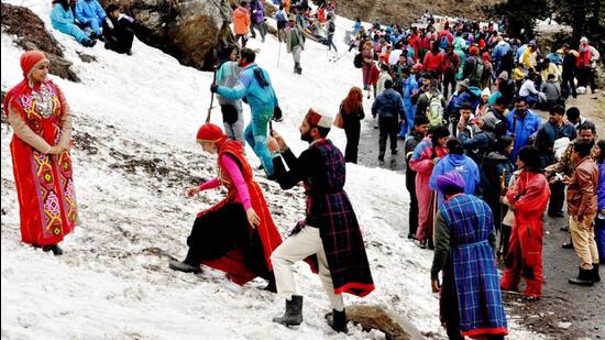 Tourists taking photographs near a snow-covered patch at Rohtang near Manali. (HT Photo)