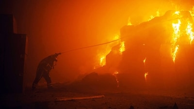 This photograph shows a rescuer putting out a fire in a building as a result of falling debris after a massive drone attack targetting Kyiv. (AFP) This photograph shows a rescuer putting out a fire in a building as a result of falling debris after a massive drone attack targetting Kyiv. (AFP)
